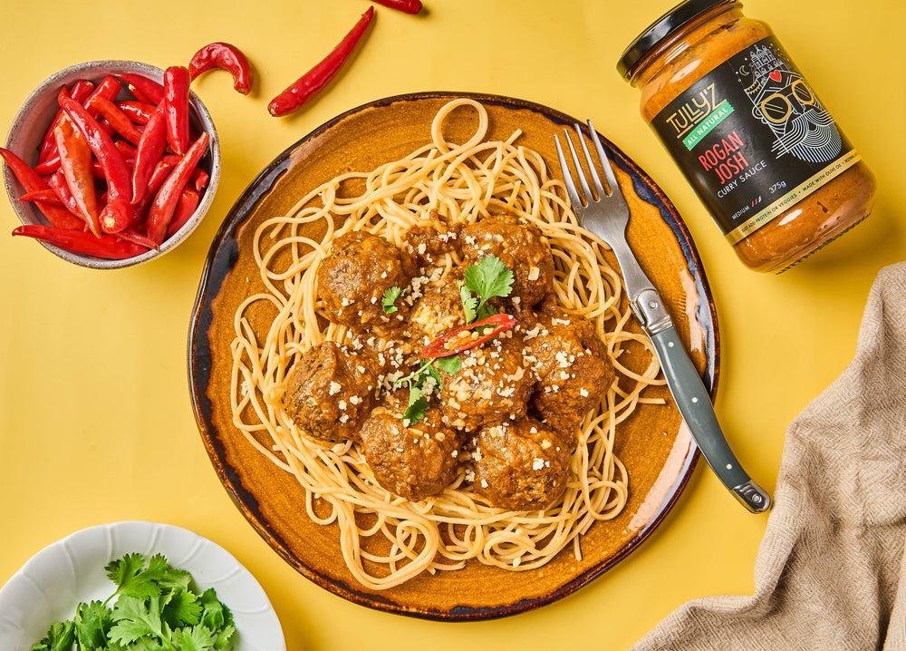 A bowl of Mumbai Meatball Spaghetti topped with feta, parmesan, and fresh coriander.