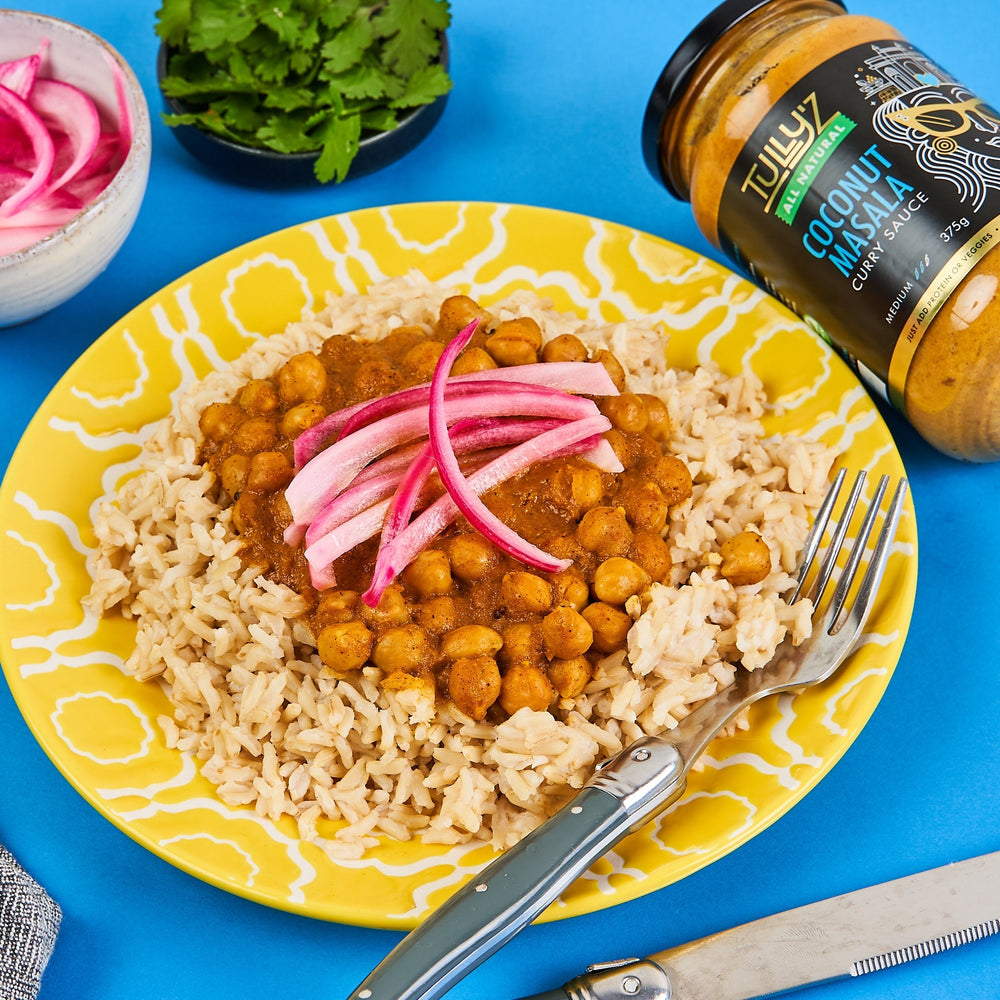 Coconut Masala Chickpea Curry served with rice and garnished with red onion and fresh coriander.