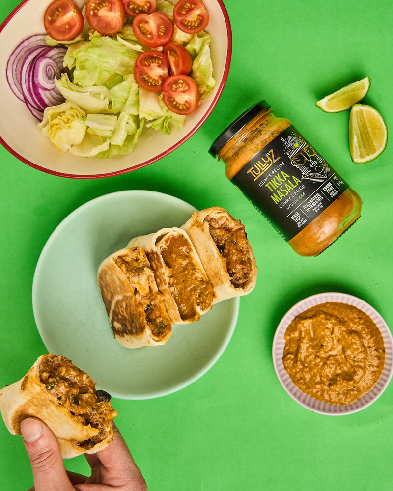 A close-up of Tikka Masala Mixed Bean Burritos filled with beans, peppers, and onions