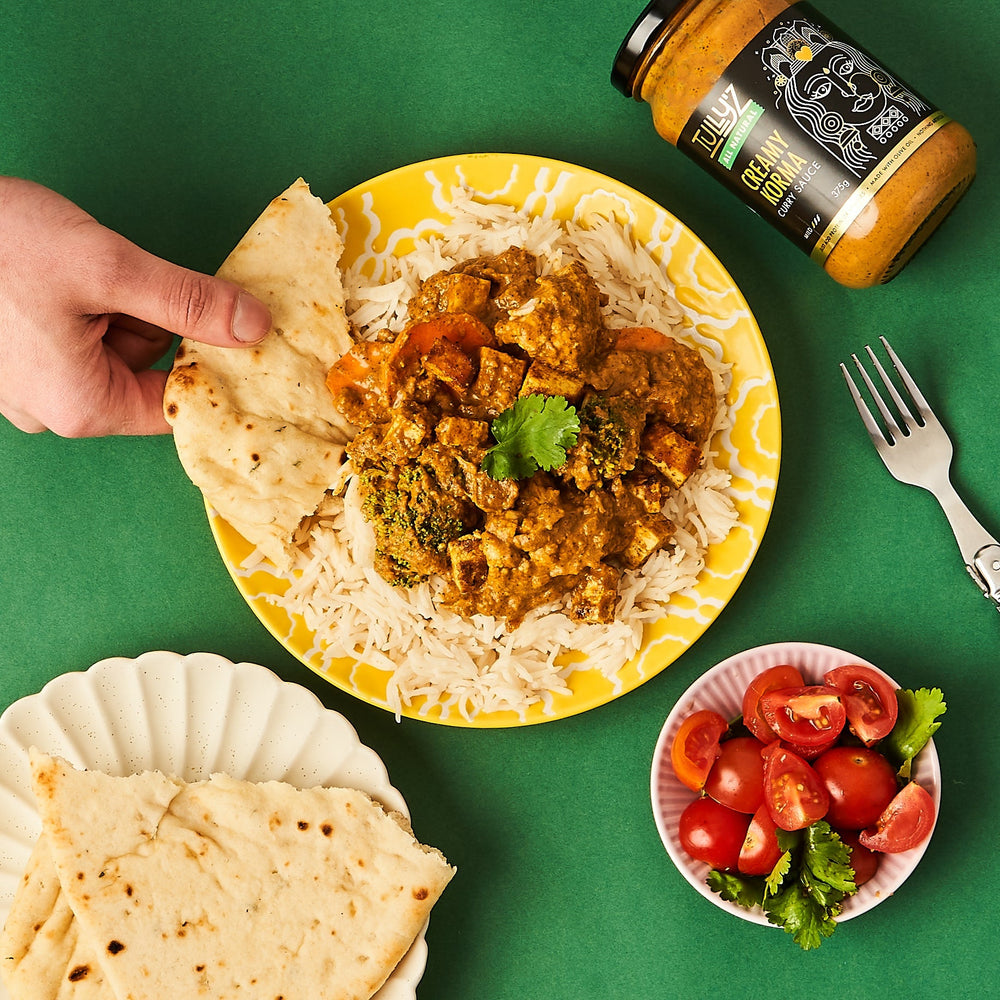 Creamy Korma Curry with Tofu, Carrots, and Broccoli, garnished with fresh coriander and diced tomato