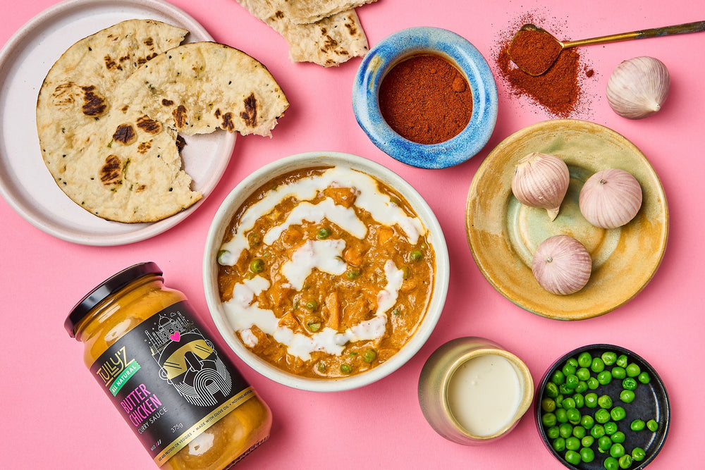 A bowl of Butter Chicken Pumpkin & Pea Curry garnished with fresh coriander.